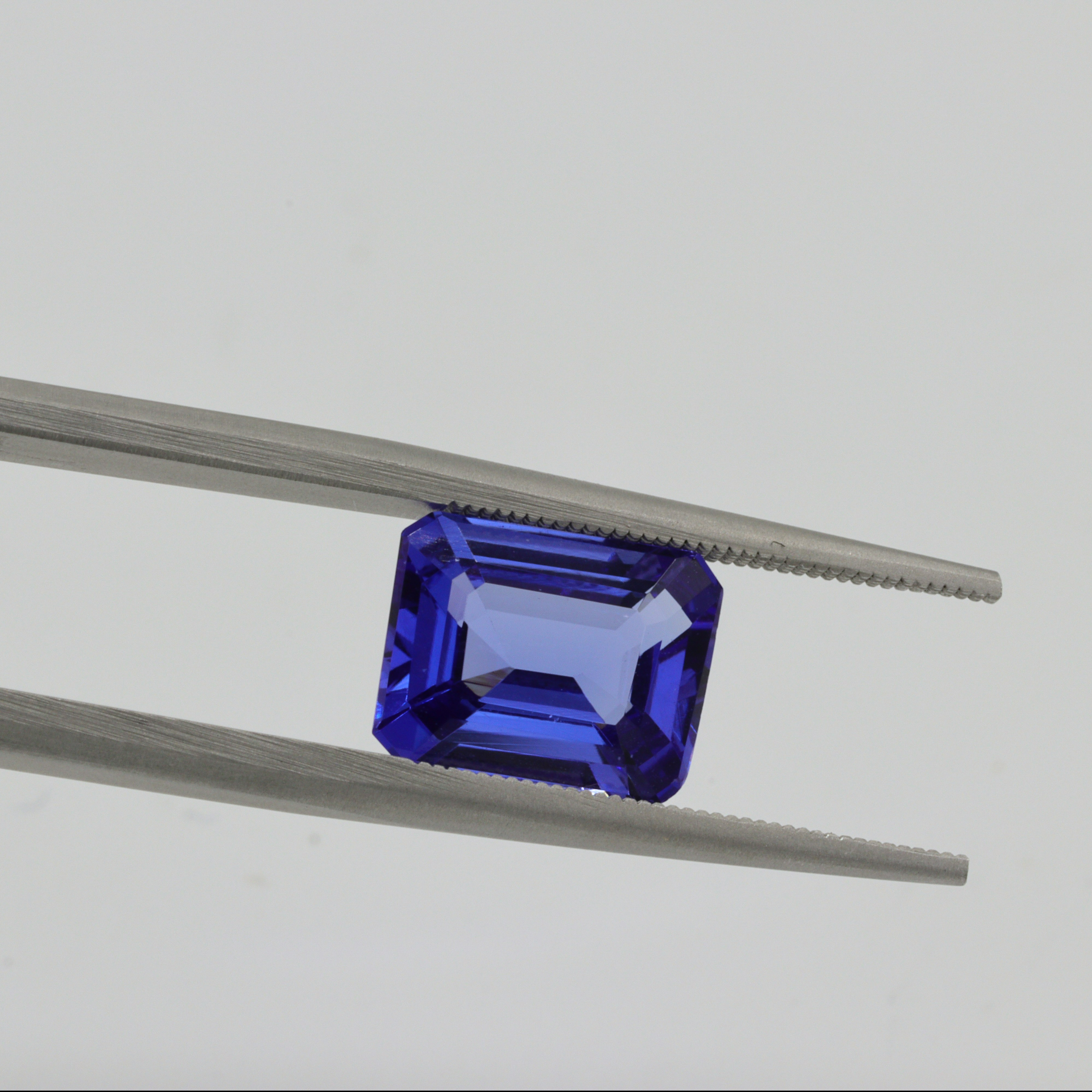 Purplish blue stone held with tweezers.